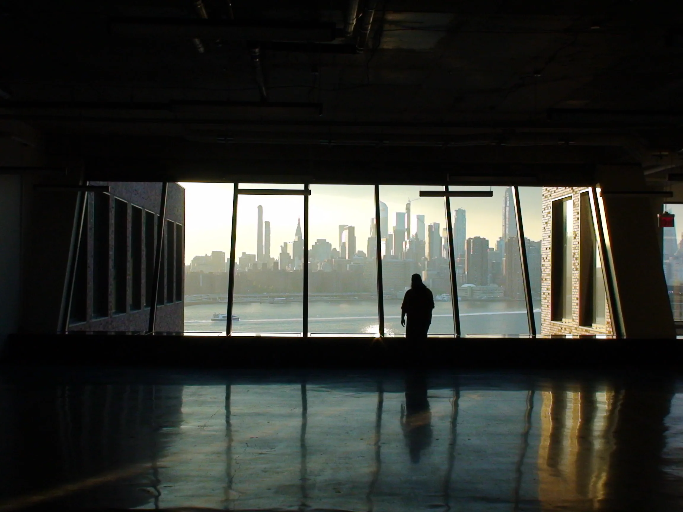 James Buret looking across the New York skyline from a dark interior